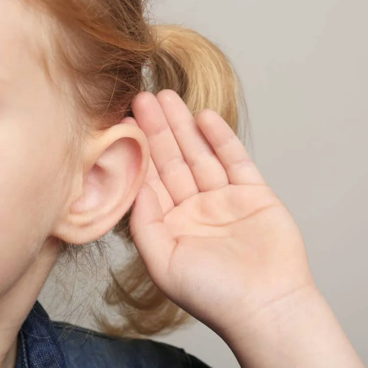 Young child cupping a hand to their ear